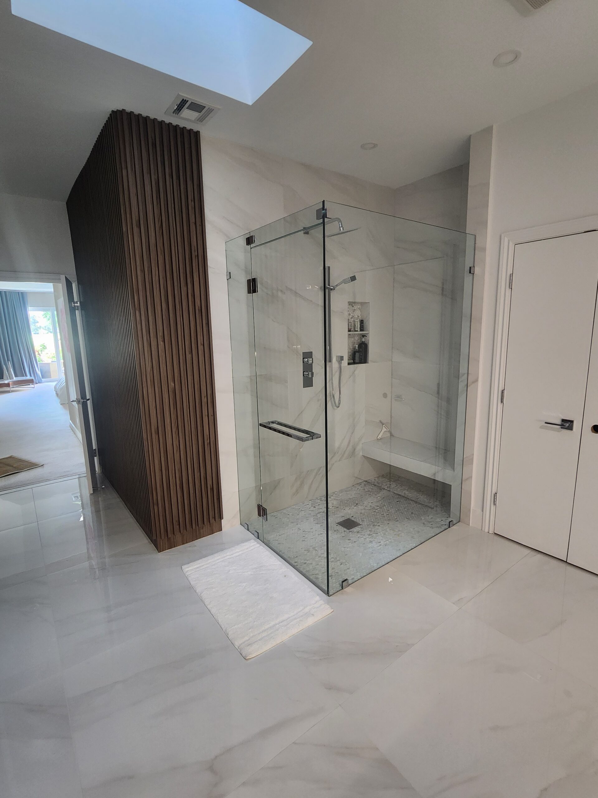  A spacious bathroom featuring a sleek glass shower door, enhancing the modern aesthetic of the room.