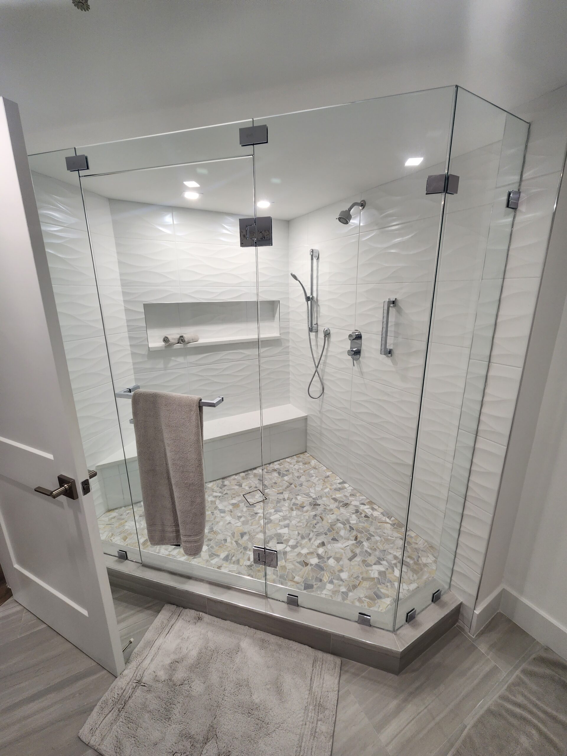 A modern bathroom featuring a glass shower door and a neatly arranged towel rack on the wall.