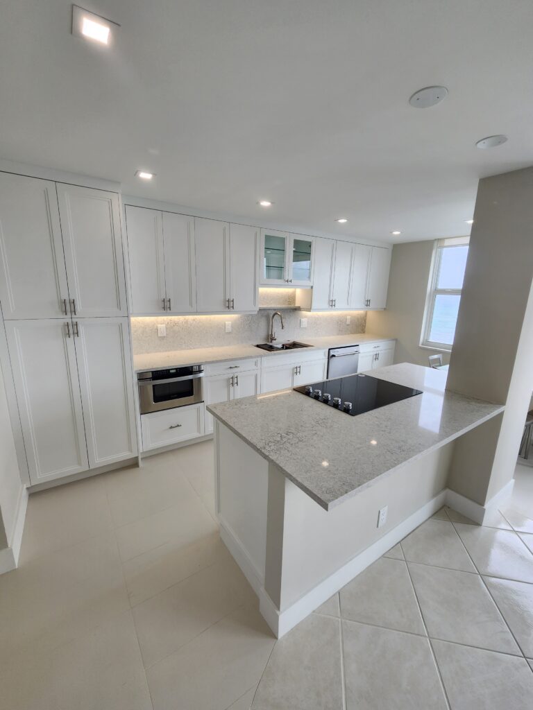 A pristine kitchen featuring white cabinets and a sleek white countertop, exuding a modern and airy atmosphere.
