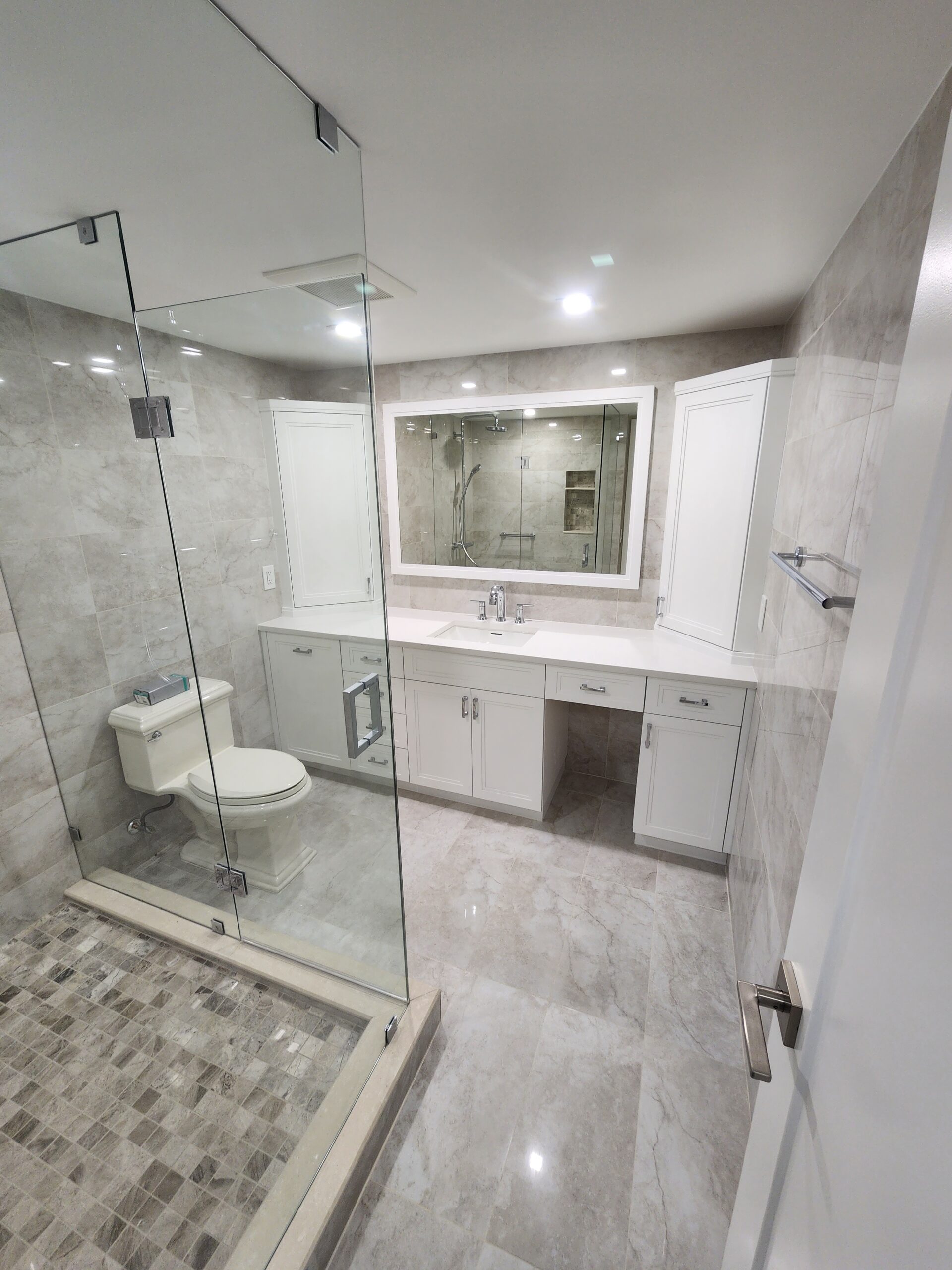 A modern bathroom featuring a glass shower door and a white toilet, showcasing a clean and minimalist design.