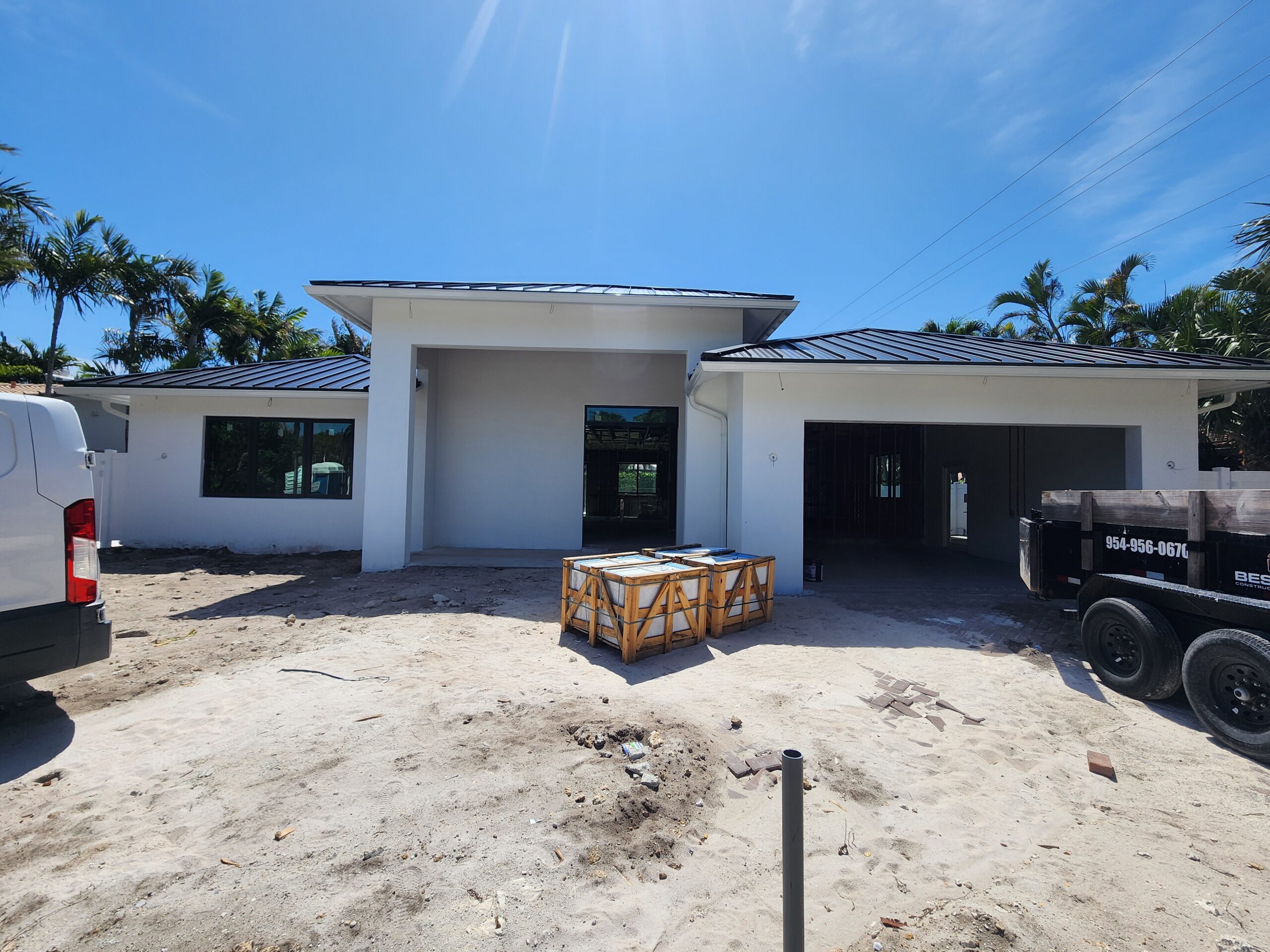 A construction site featuring a house under construction in the center of a spacious lot, surrounded by raw materials.
