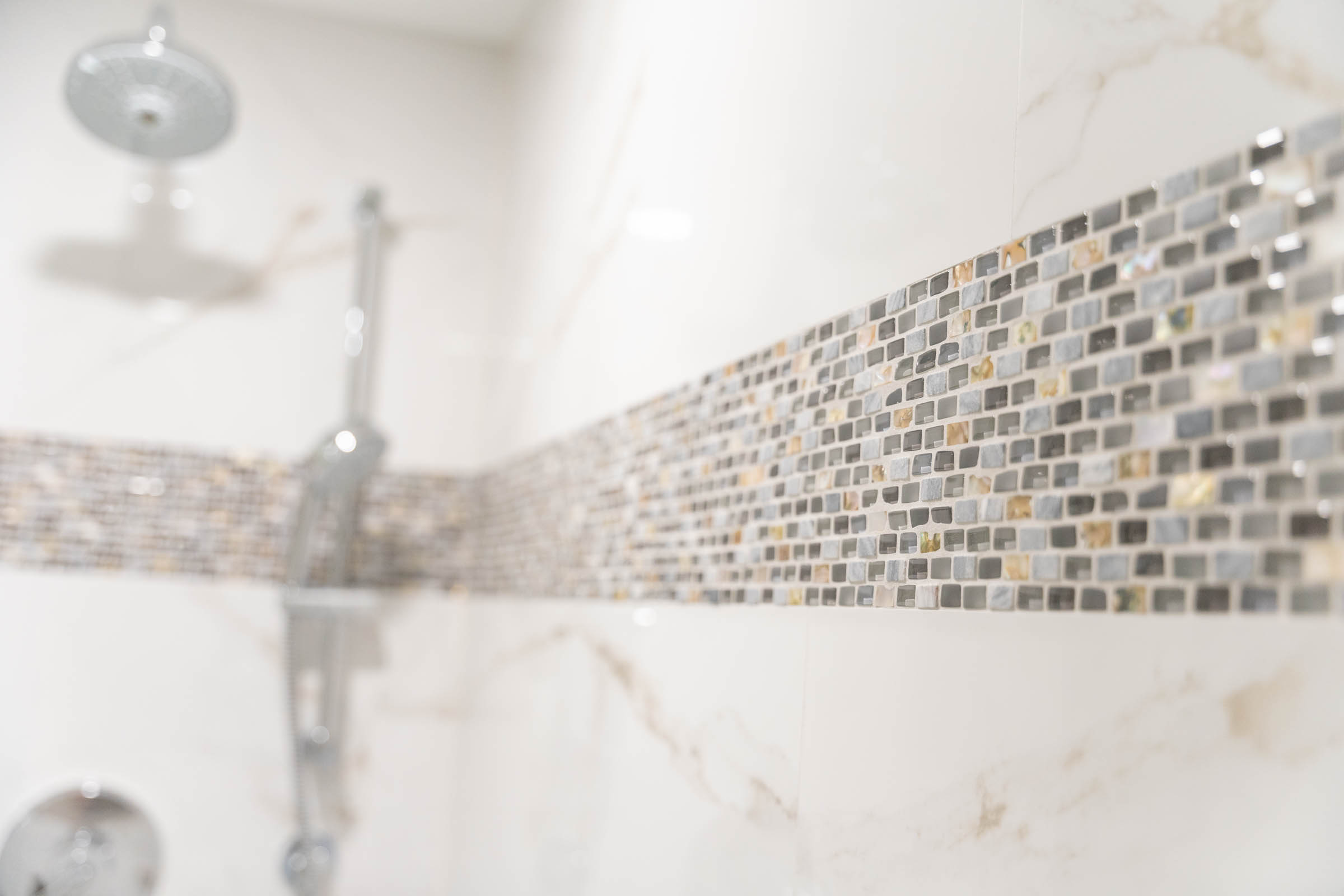 A modern shower featuring a colorful mosaic tile wall and a sleek shower head, creating a stylish bathing space.