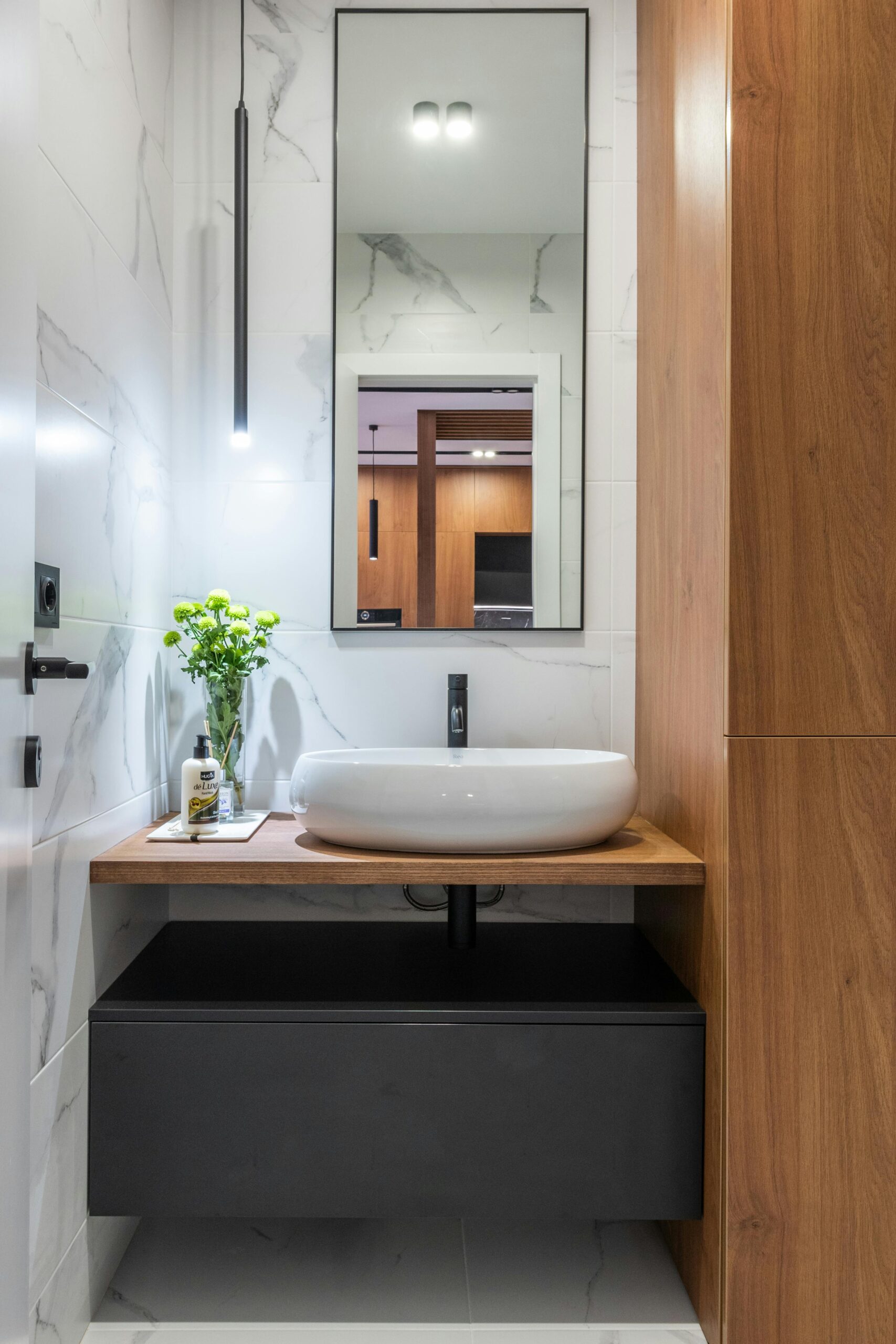 A contemporary bathroom featuring wooden cabinets and a sleek white sink, showcasing a blend of style and functionality.
